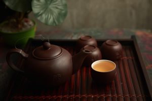 Brown Cup Beside Brown Ceramic Teapot on Wooden Table